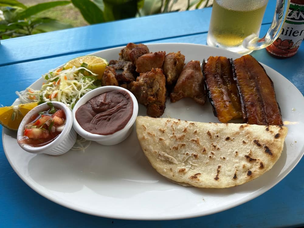 Casado con chuleta de cerdo, maduro y frijoles sobre mesa azul