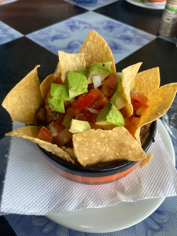 Chifrijo servido en tazón negro con aguacate