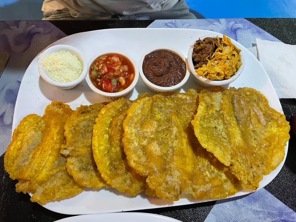 Plato de patacones con cuatro salsas en mesa azul mosaico
